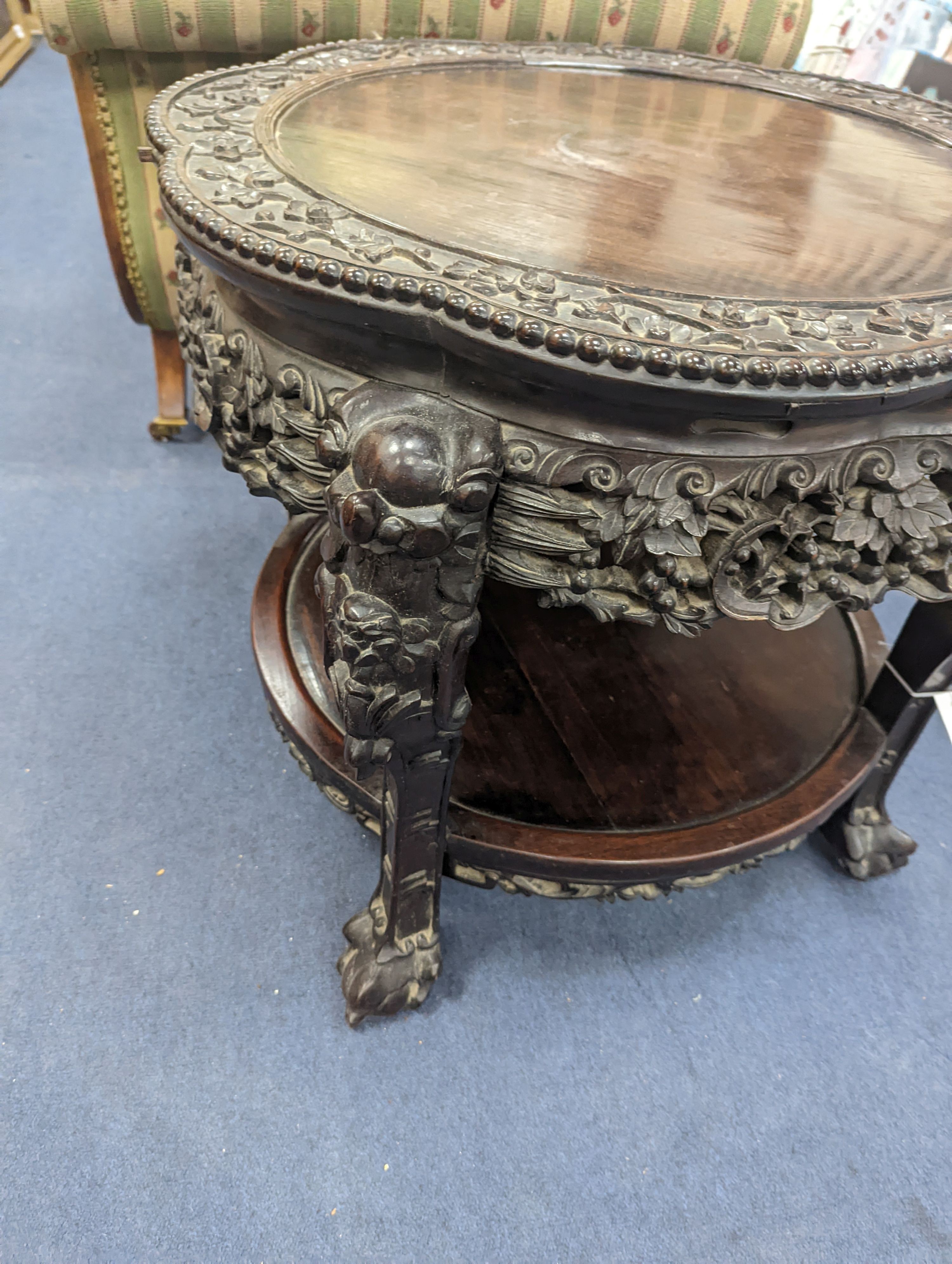 An early 20th century Chinese carved hardwood two tier table, diameter 64cm, height 56cm